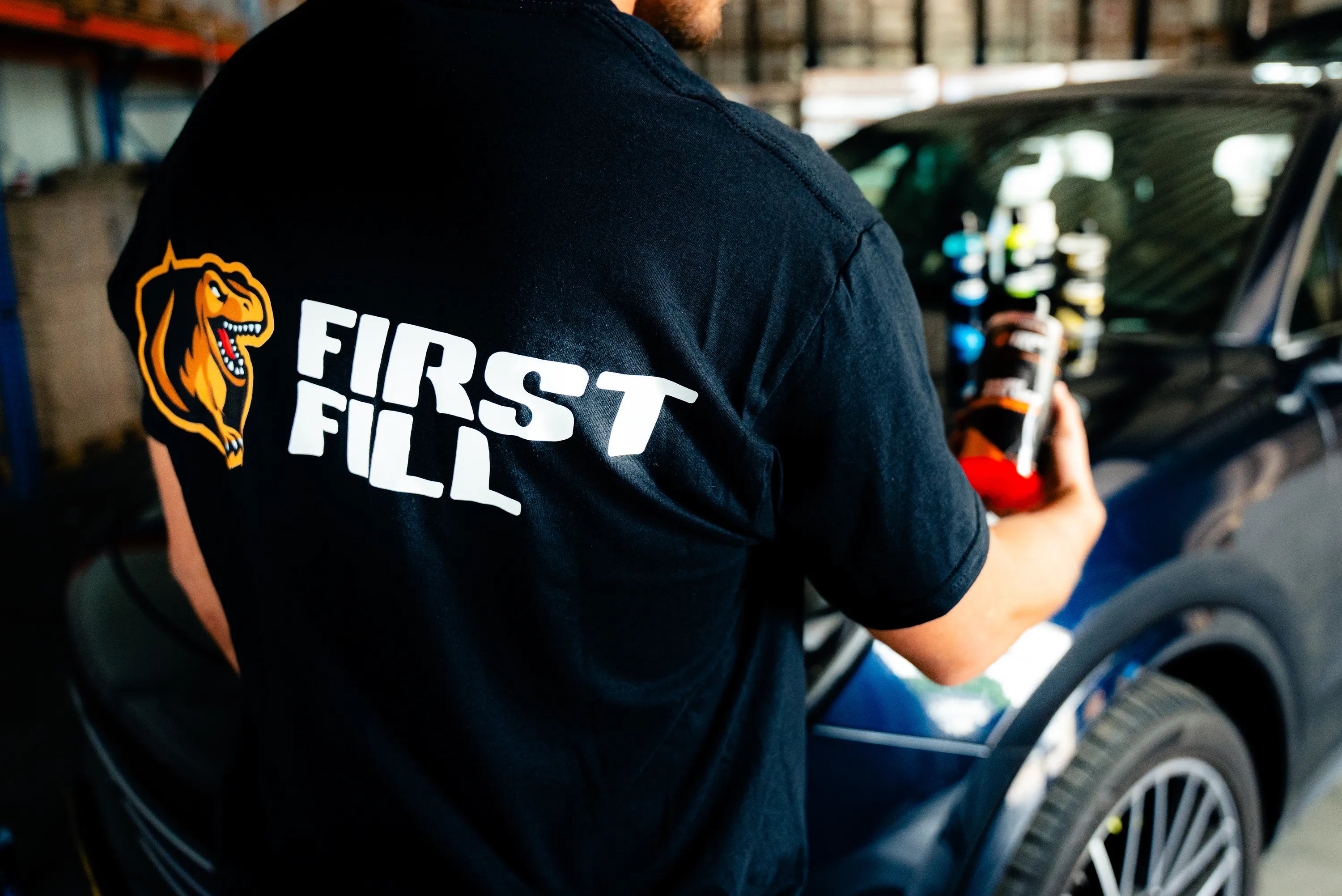 First Fill specialist met car care producten naast een auto